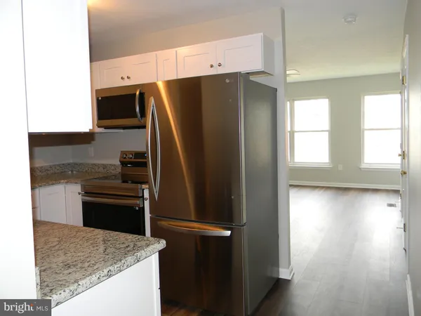 a kitchen with stainless steel appliances granite countertop a refrigerator a stove and a sink with wooden floor