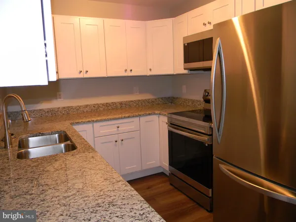 a kitchen with granite countertop a sink stove and refrigerator