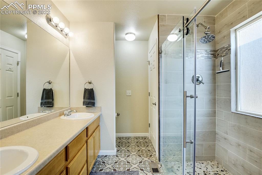 6446 Dancing Moon Way Colorado Springs, CO 80911 - Photo 17 of 42 a bathroom with a double vanity sink mirror and shower