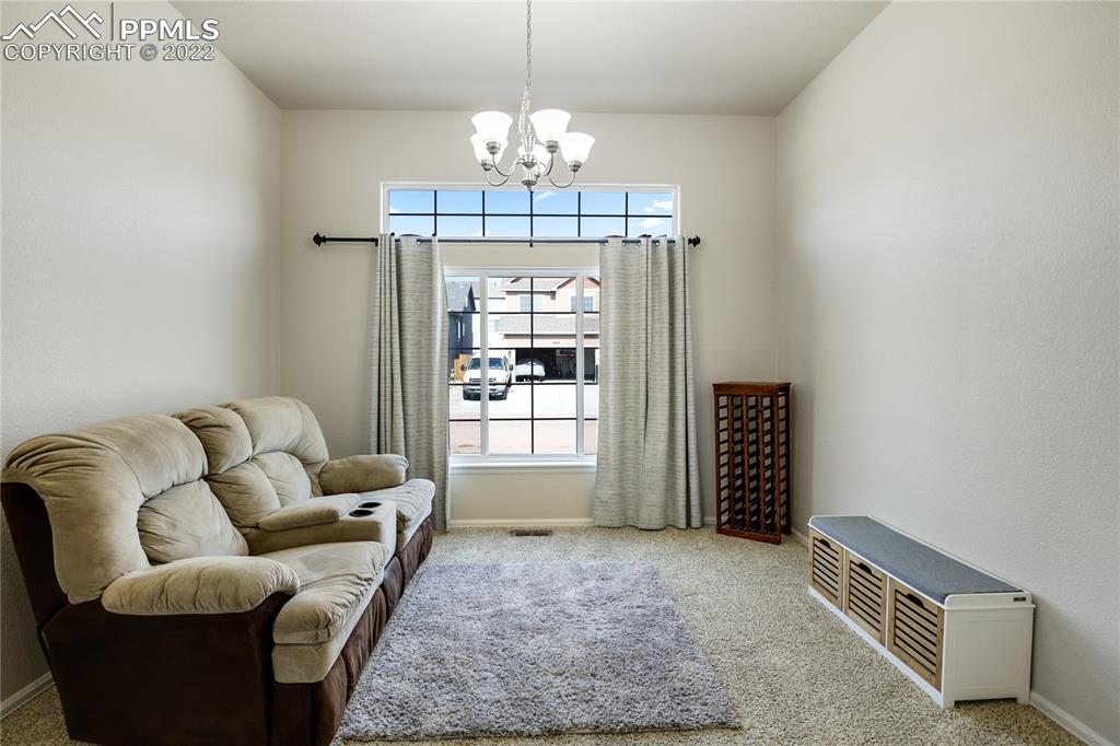6446 Dancing Moon Way Colorado Springs, CO 80911 - Photo 5 of 42 a living room with furniture a chandelier and a dining table