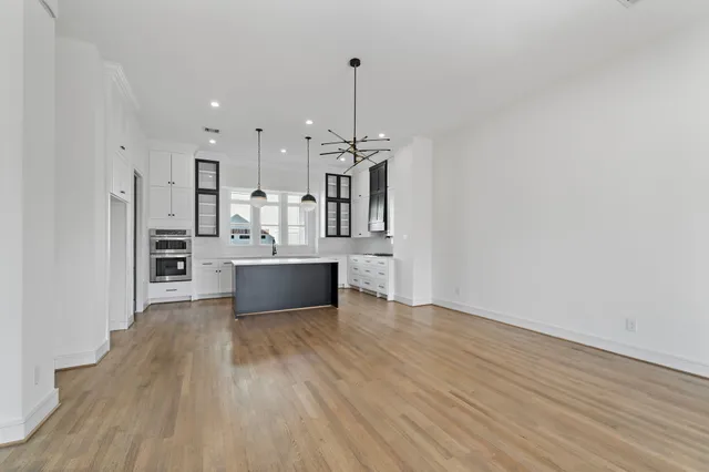 a large kitchen with stainless steel appliances a large counter top a sink and a refrigerator