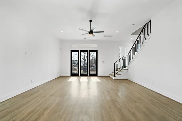 a view of an empty room with wooden floor stairs