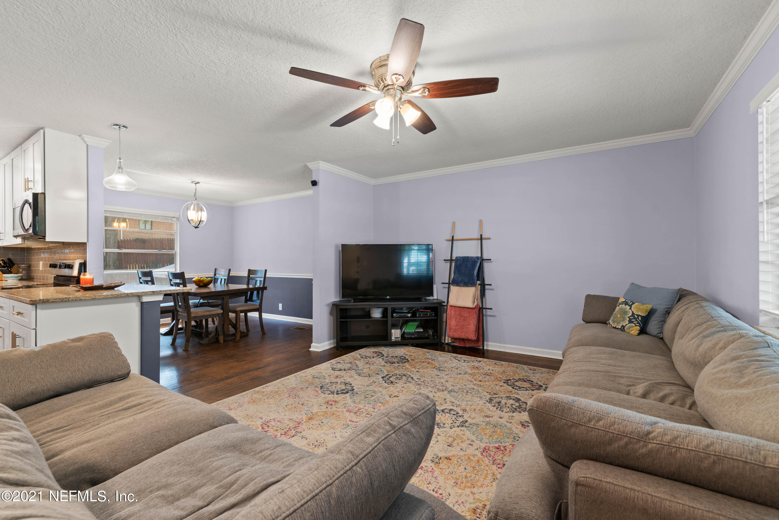 6434 Heidi Road Jacksonville, FL 32277 - Photo 9 of 32 a living room with furniture and a flat screen tv with kitchen view
