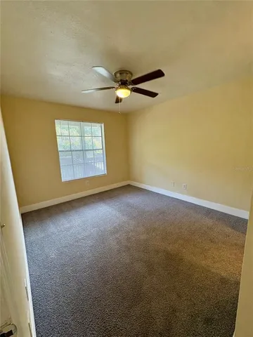 an empty room with windows and ceiling fan