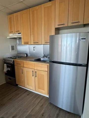 a kitchen with stainless steel appliances granite countertop a refrigerator a stove top oven and cabinets