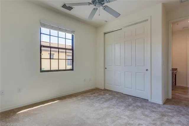 an empty room with a ceiling fan and windows