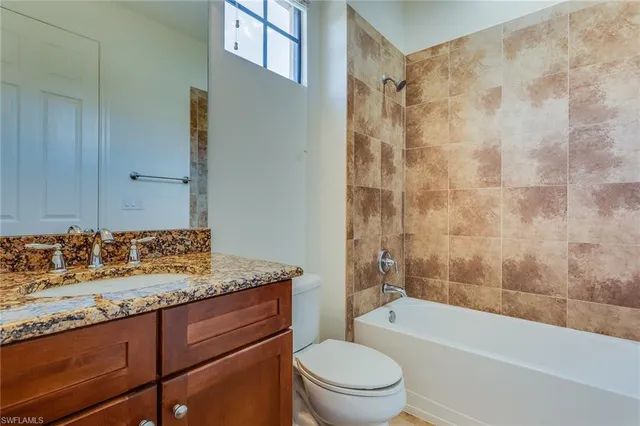 a bathroom with a granite countertop sink toilet mirror vanity and bathtub