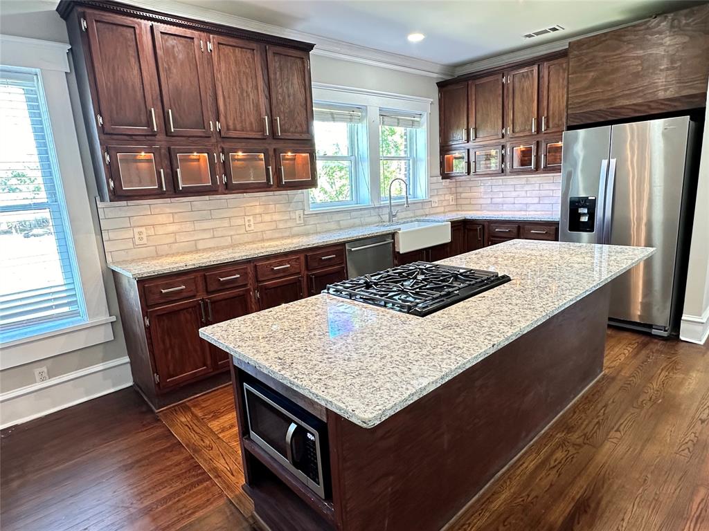 a kitchen with stainless steel appliances granite countertop a stove window and cabinets