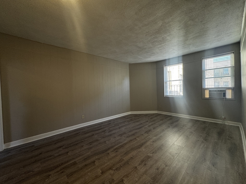1870 Beacon Street, Unit 54 Brookline, MA 02445 - Photo 2 of 13 an empty room with wooden floor and windows