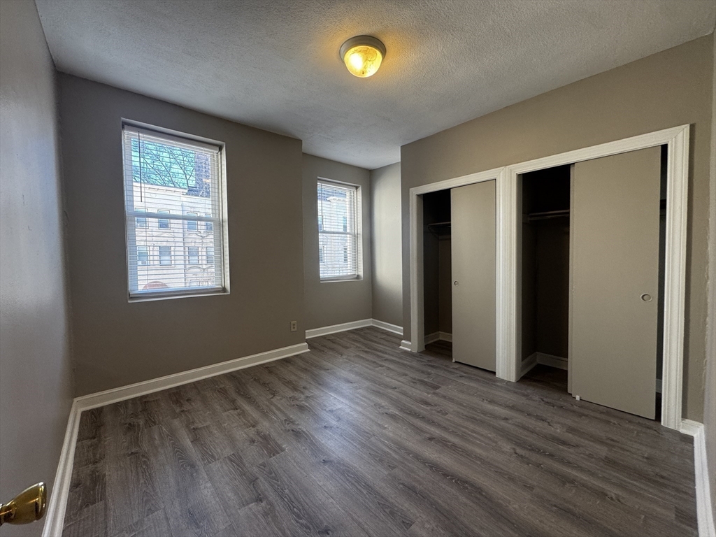1870 Beacon Street, Unit 54 Brookline, MA 02445 - Photo 4 of 13 an empty room with wooden floor and windows