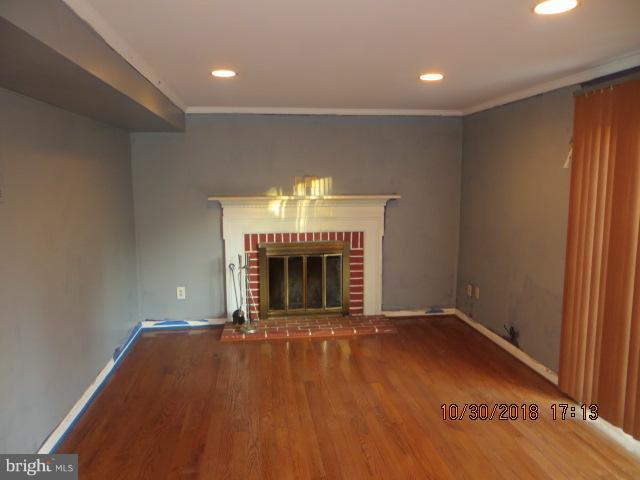 6923 Pinecrest Road Baltimore, MD 21228 - Photo 14 of 14 an empty room with a fireplace and chandelier fan