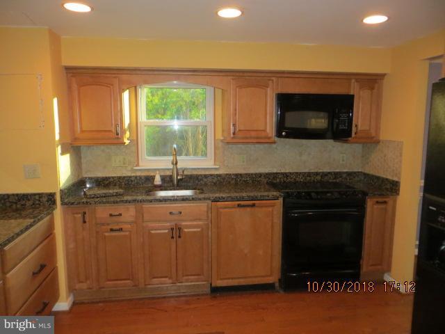 6923 Pinecrest Road Baltimore, MD 21228 - Photo 4 of 14 a kitchen with granite countertop a stove a sink and a microwave