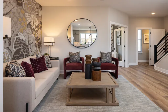 a living room with furniture a mirror and a wooden floor