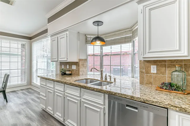 a kitchen with granite countertop a sink and white cabinets