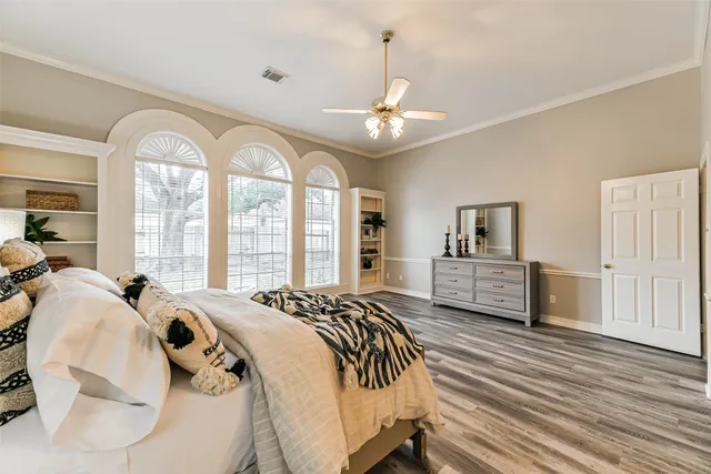 a spacious bedroom with a bed a dresser and large windows
