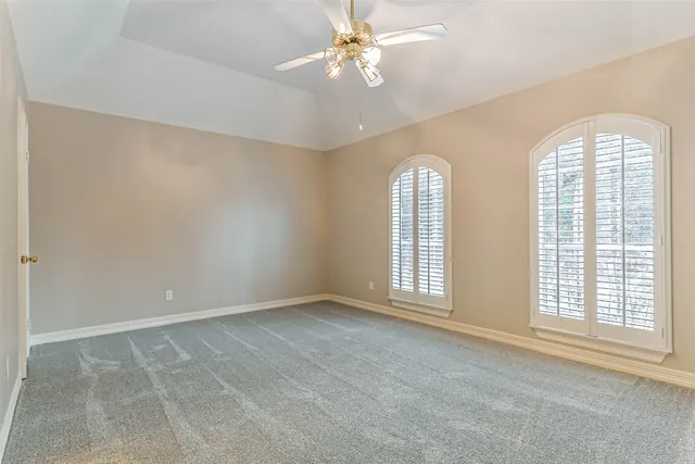 an empty room with windows and chandelier fan
