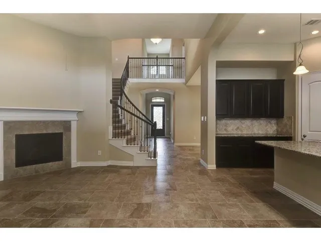 a view of an empty room and kitchen with fireplace