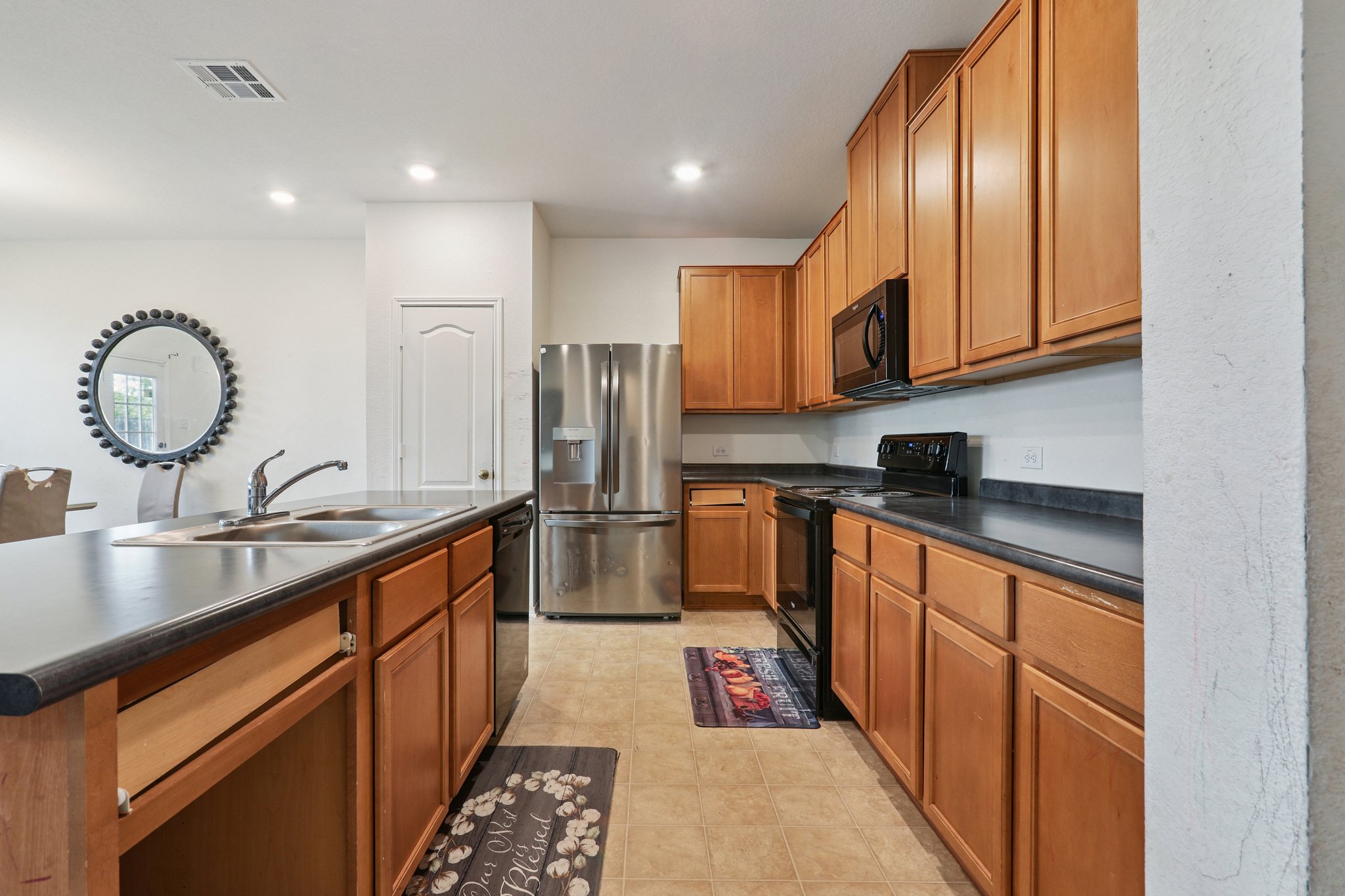 13817 Eleanor Roosevelt Street Manor, TX 78653 - Photo 10 of 35 a kitchen with stainless steel appliances granite countertop a sink a stove and a refrigerator