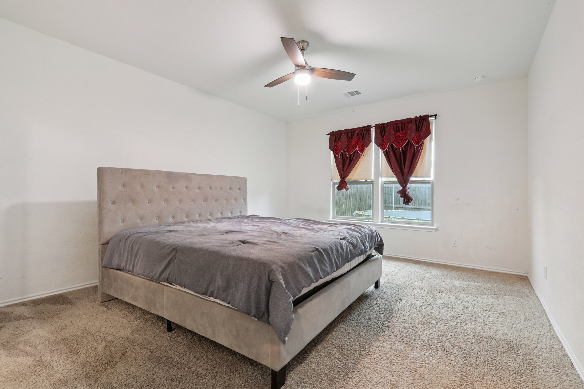 13817 Eleanor Roosevelt Street Manor, TX 78653 - Photo 24 of 35 a spacious bedroom with a bed and a painting on the wall