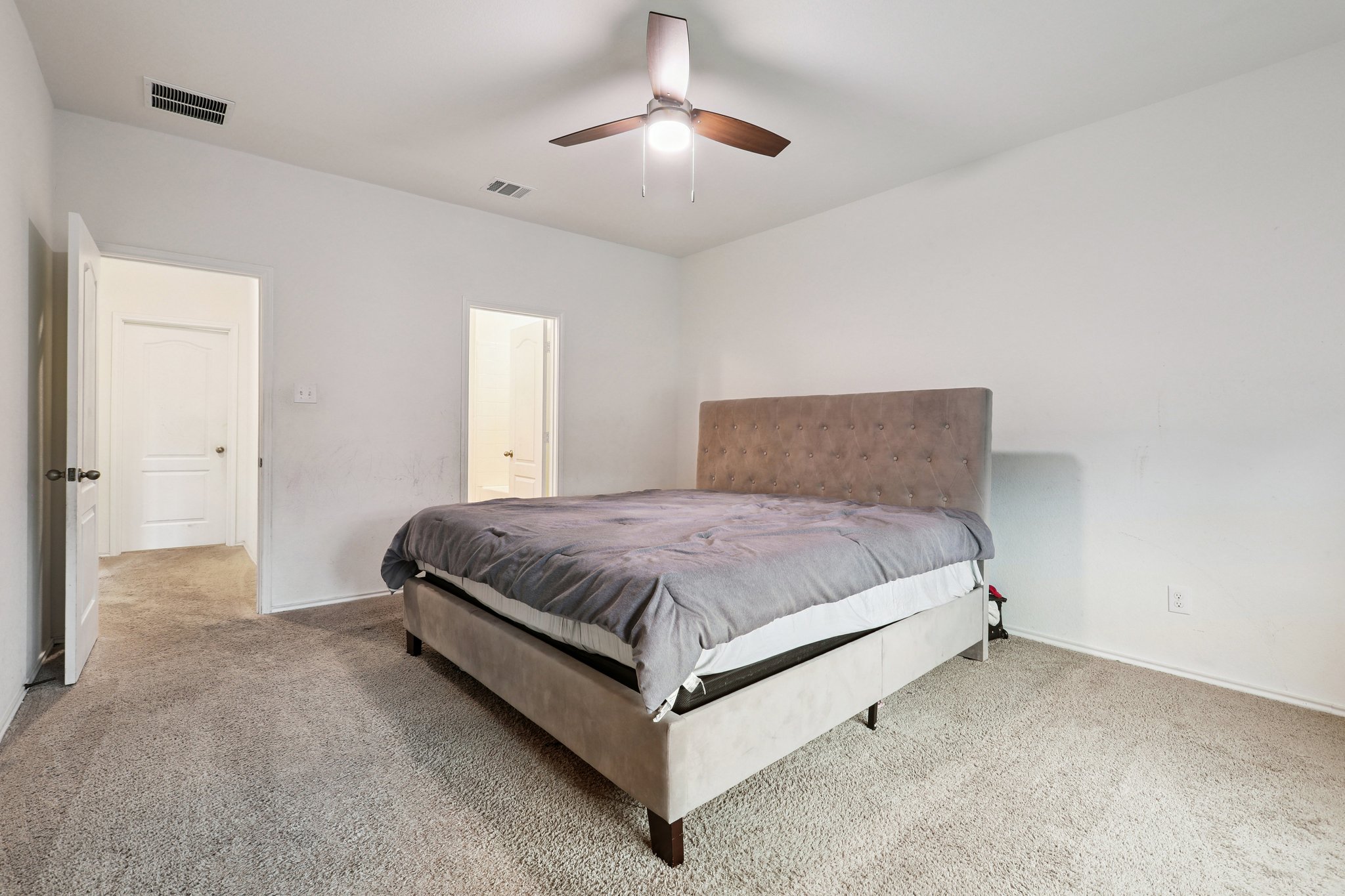 13817 Eleanor Roosevelt Street Manor, TX 78653 - Photo 25 of 35 a spacious bedroom with a bed and a chandelier