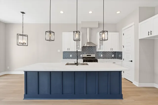 a kitchen with kitchen island white cabinets with stainless steel appliances