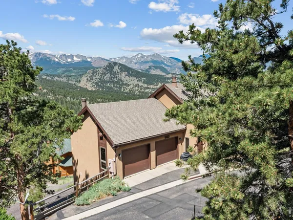an aerial view of a house with a yard and mountain view in back