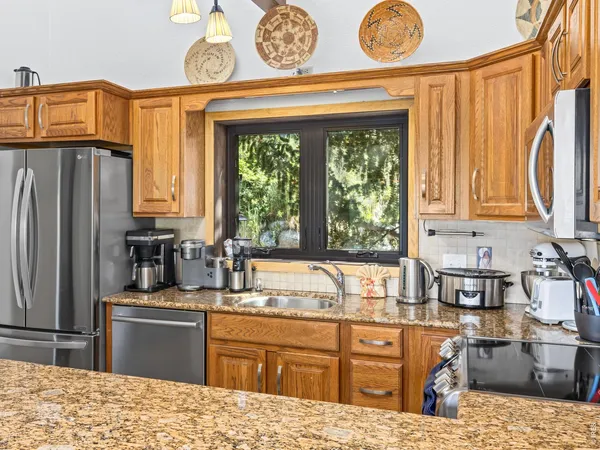 a kitchen with stainless steel appliances kitchen island granite countertop a refrigerator stove top oven and sink