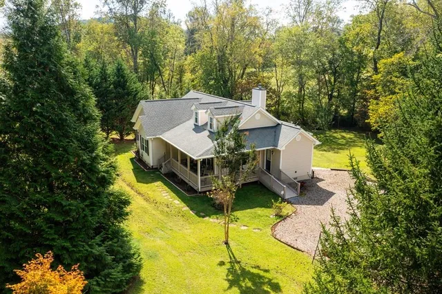 a aerial view of a house with swimming pool and trees in the background
