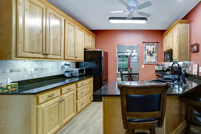 a kitchen with stainless steel appliances granite countertop wooden cabinets a dining table and chairs