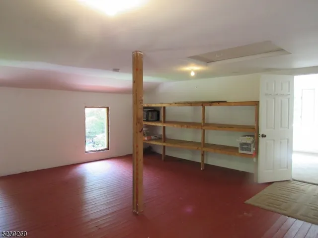 an empty room with wooden floor closet and windows