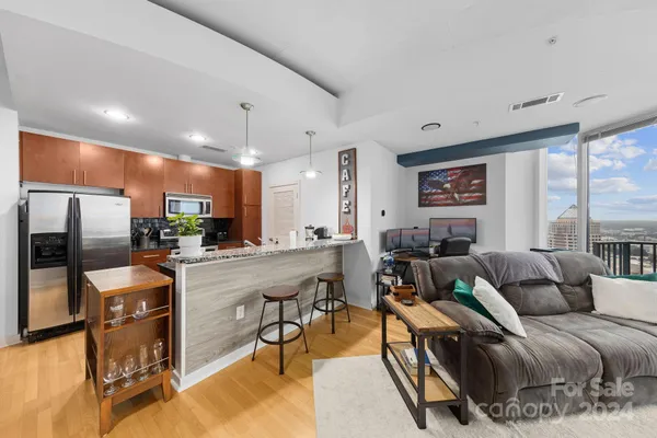 a living room with furniture a large window and stainless steel appliances