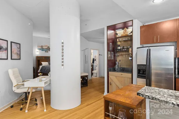 a living room with stainless steel appliances kitchen island granite countertop a refrigerator a stove and a dining table with wooden floor