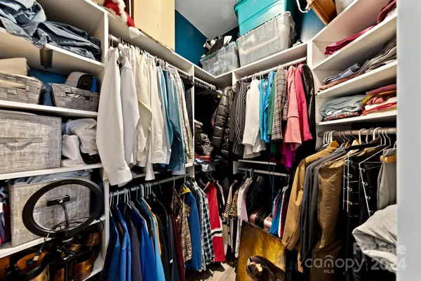 a view of walk in closet with clothes and shoes