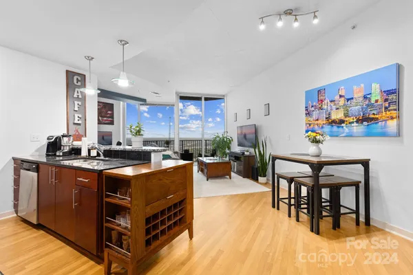a kitchen with stainless steel appliances granite countertop a stove a refrigerator a dining table and chairs with wooden floor