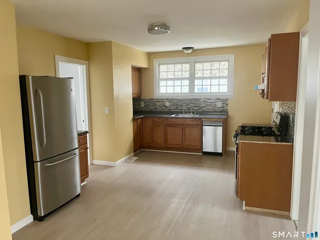 a kitchen with stainless steel appliances granite countertop a refrigerator a stove a sink and a granite counter tops with a window