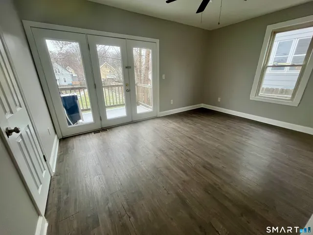 a view of an empty room with wooden floor and a window