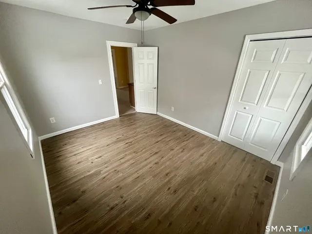 en empty room with wooden floor and fan