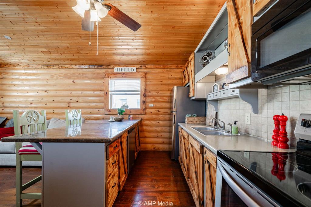 941 Harold Street Albany, TX 76430 - Photo 11 of 22 a kitchen with stainless steel appliances granite countertop a sink and a wooden cabinets