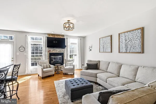 a living room with furniture wooden floor and kitchen view