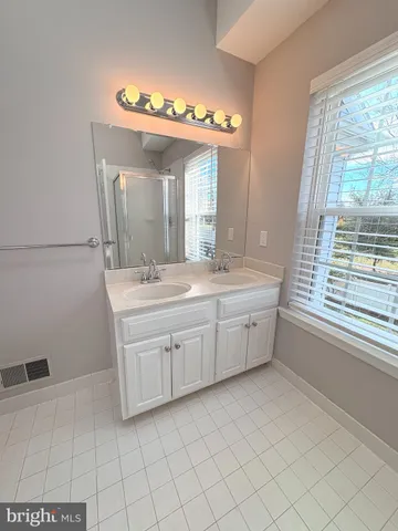 a bathroom with a double vanity sink mirror and window