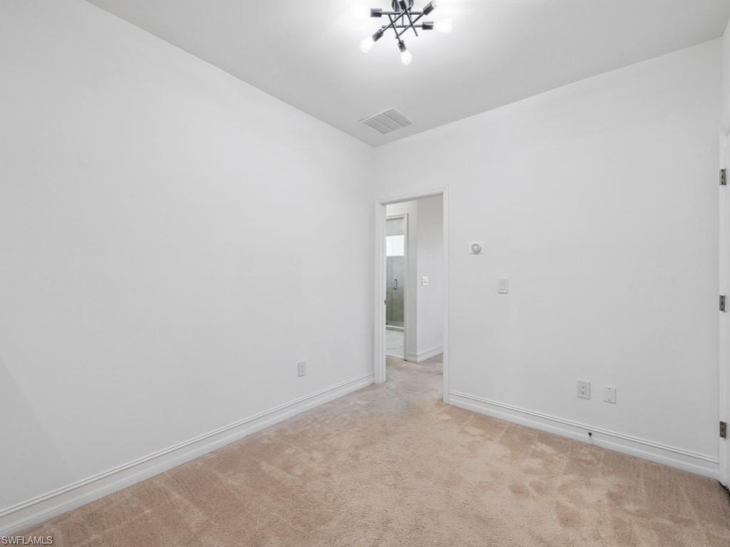 7591 Morgan Way Naples, FL 34119 - Photo 14 of 27 Carpeted empty room with an inviting chandelier