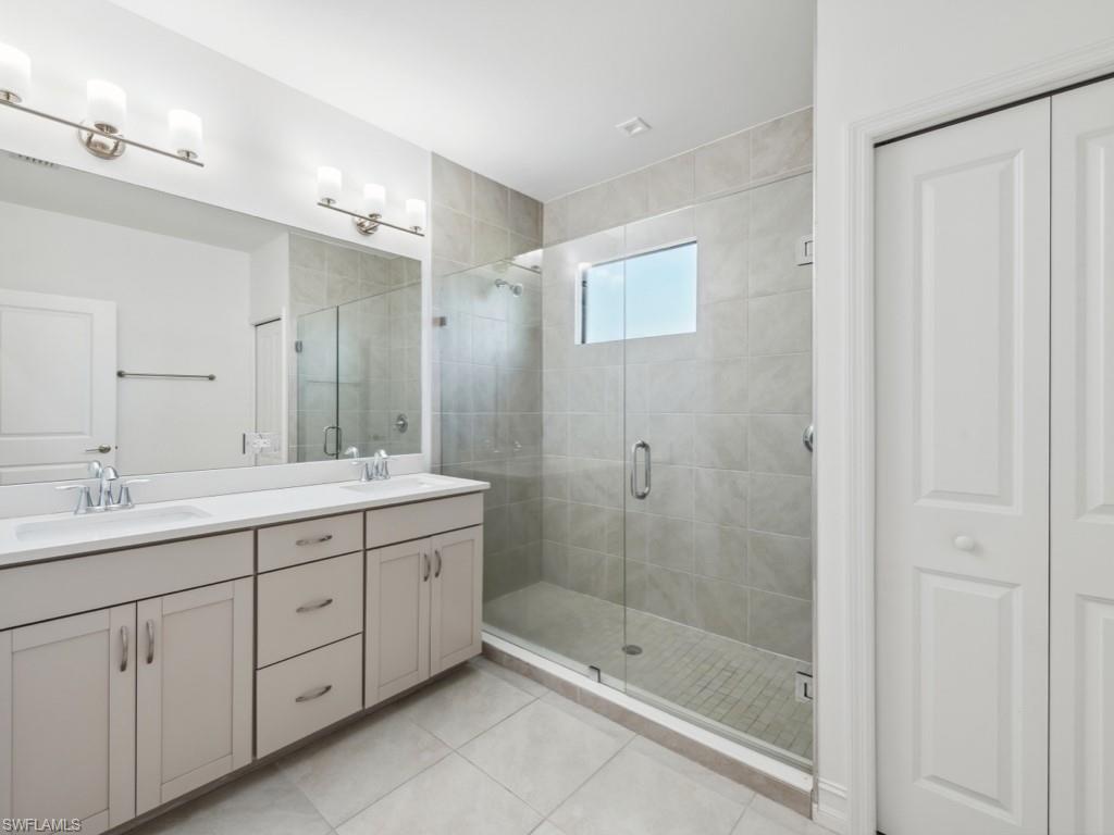 7591 Morgan Way Naples, FL 34119 - Photo 19 of 27 Bathroom featuring tile patterned flooring, vanity, and a shower with shower door
