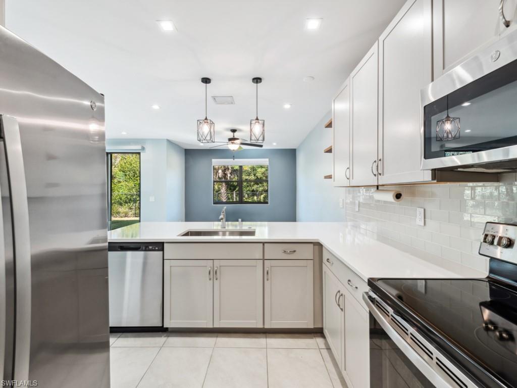 7591 Morgan Way Naples, FL 34119 - Photo 6 of 27 Kitchen featuring pendant lighting, sink, light tile patterned floors, stainless steel appliances, and kitchen peninsula