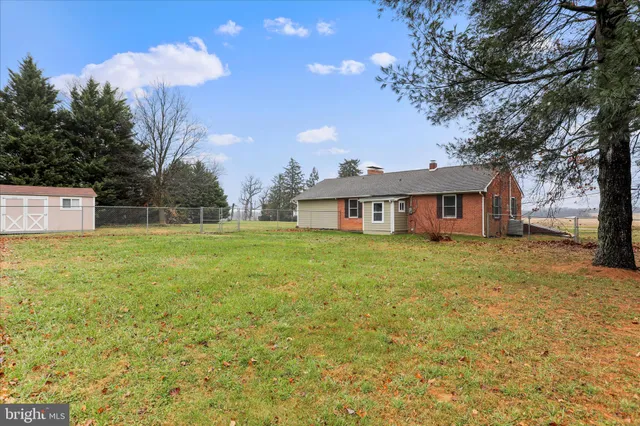 a house that is sitting in the grass with large trees