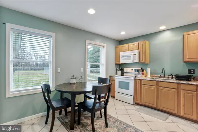 a kitchen with a dining table chairs and white appliances
