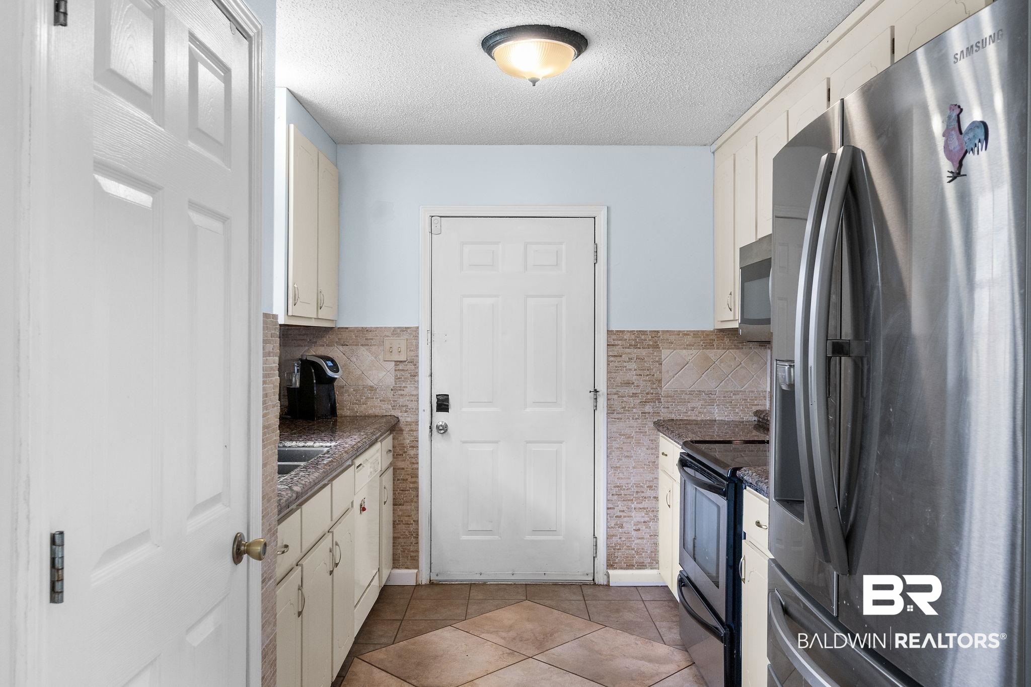 33135 Collier Road Lillian, AL 36549 - Photo 10 of 30 Kitchen with stainless steel appliances, light tile patterned flooring, and a textured ceiling