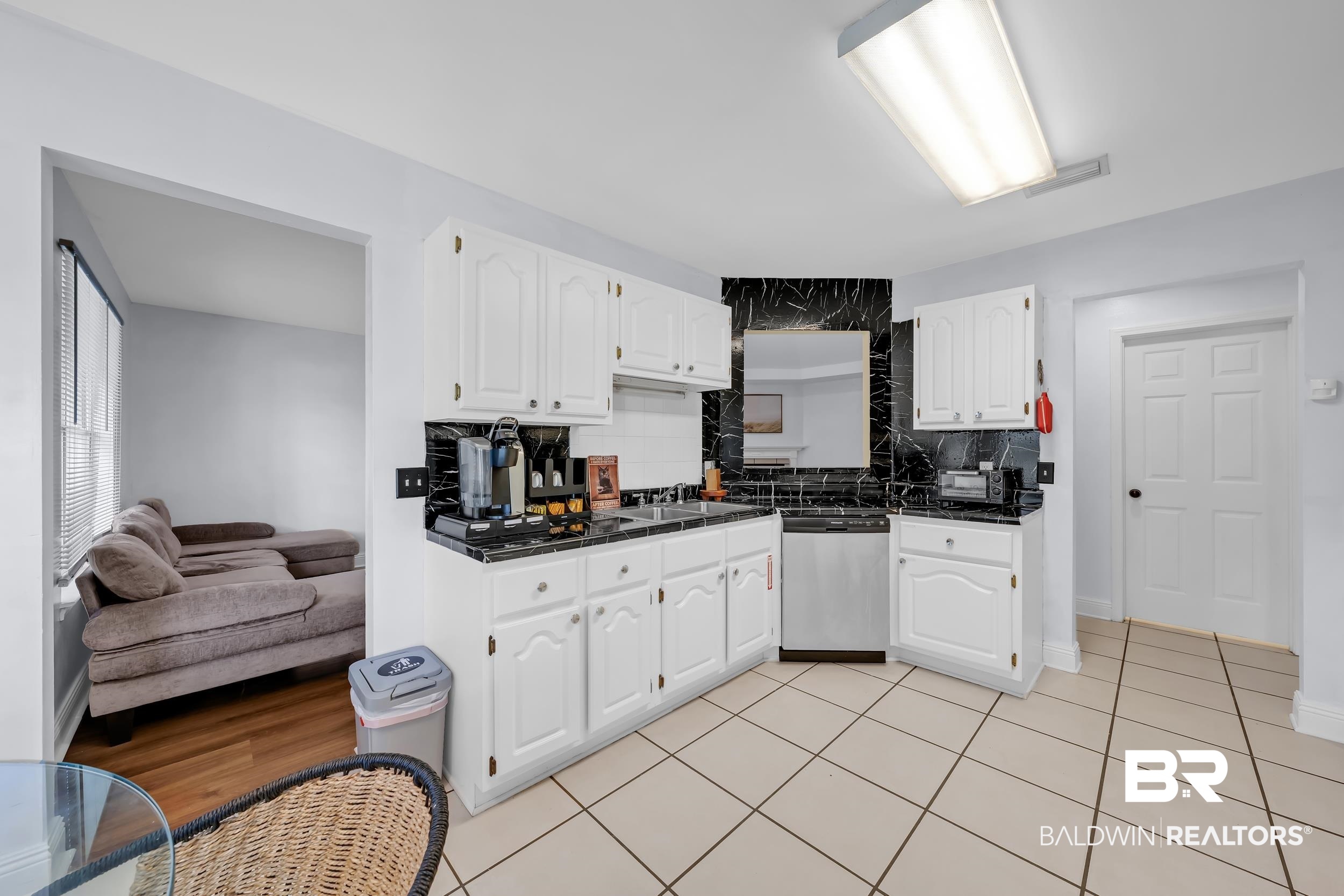 509 Loblolly Court Foley, AL 36535 - Photo 10 of 26 Kitchen featuring white cabinetry, dark countertops, a black patterned backsplash, stainless steel dishwasher, and square tile flooring