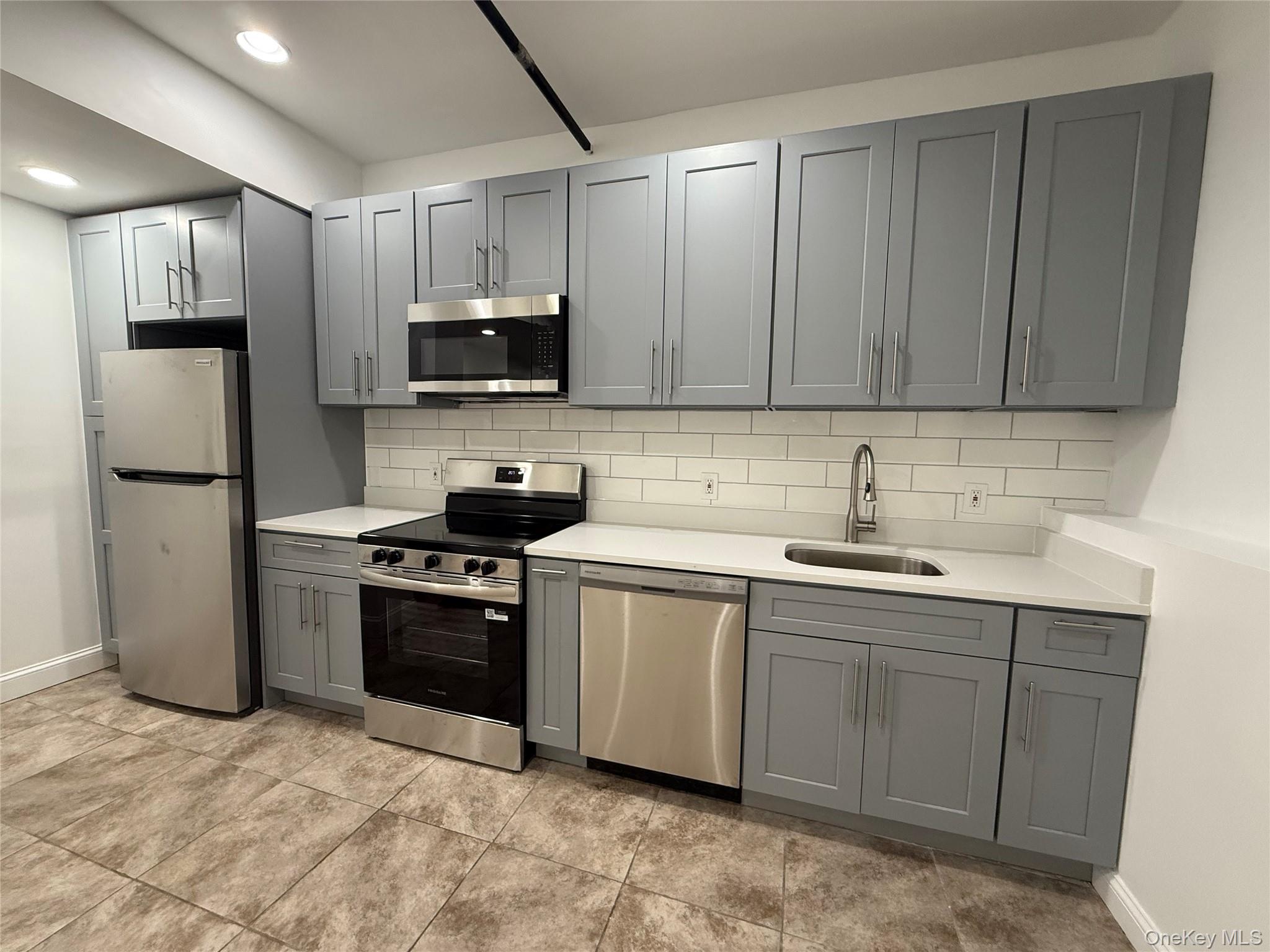 94 4th Avenue Bay Shore, NY 11706 - Photo 2 of 6 a kitchen with stainless steel appliances granite countertop a stove top oven a sink and dishwasher a refrigerator with wooden cabinets