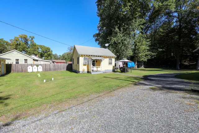 a view of house with a big yard and large trees
