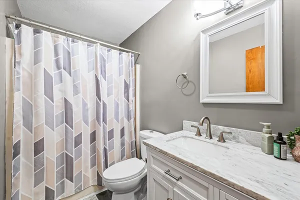 a bathroom with a granite countertop sink a toilet and a mirror